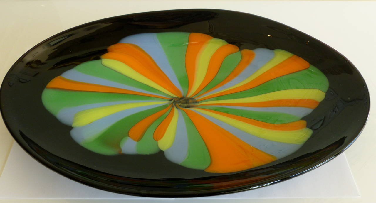 This gorgeous oval Murano Italian vintage serving platter or centerpiece bowl has black glass for the dramatic background. The luminous exploding center blossom flower in the luscious colors of orange, yellow, periwinkle blue and green are a