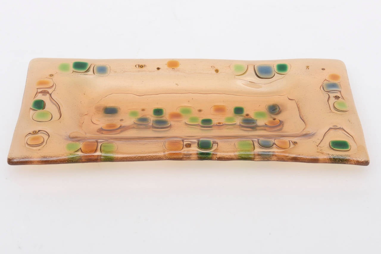 This wonderful piece of fused Higgins glass is on the rare side. It is an early work of Francis and Michael Higgins work; collectable American glass artists.
The wonderful colors are amber with dots of two shades of green, blue, orange,