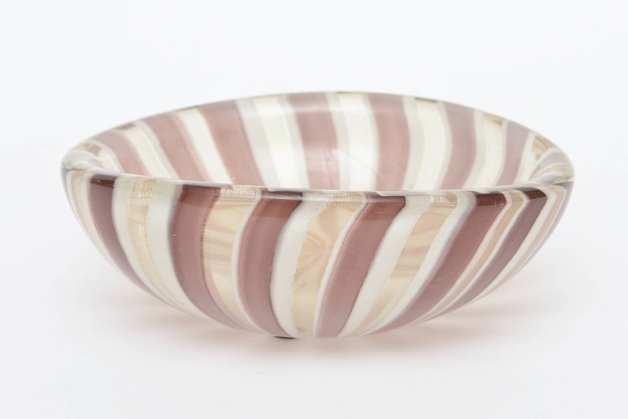This very glorious and early bowl form has the powdered gold showing amongst the perfectly executed striped canes in amethyst brown and gold against a off-white background.
A true treasure and on the rarer side.
This was made by the celebrated and