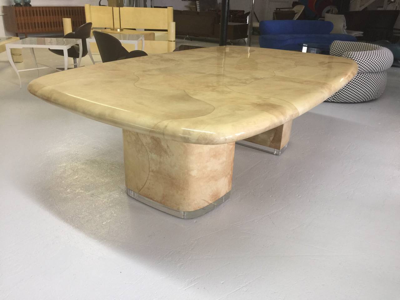 Massive goatskin dining room table by Steve Chase.
Featuring rounded rectangular top
with bullnose edge supported by 
two pedestals on 3" thick solid Lucite base.
Two 20" matching extension boards.
