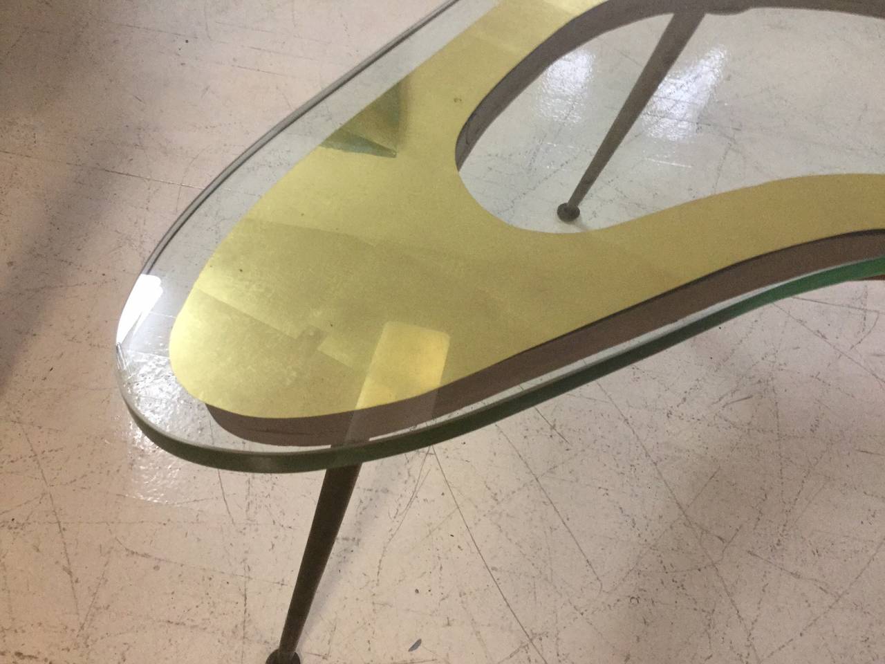 Super elegant Italian coffee table in a free-form style of Fontana Arte.
Featuring a boomerang shaped thick glass top with a reversed gold.
Leaf edge supported by a slender tapered brass legs with sabots.