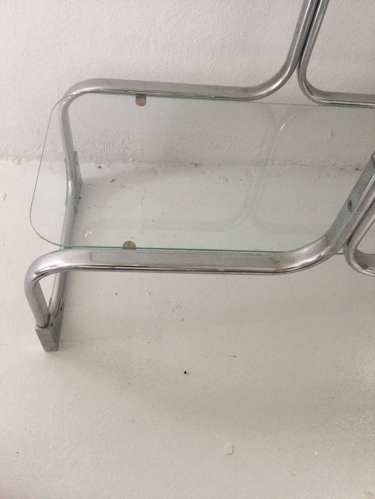 Pair of chromed steel and glass étagerès by Tricom,
featuring bent flat steel structure with 
four 14"d x 34"w, 1/4" thick glass shelves
with rounded corners.
16.25"h between top shelves,
15.25"h between bottom