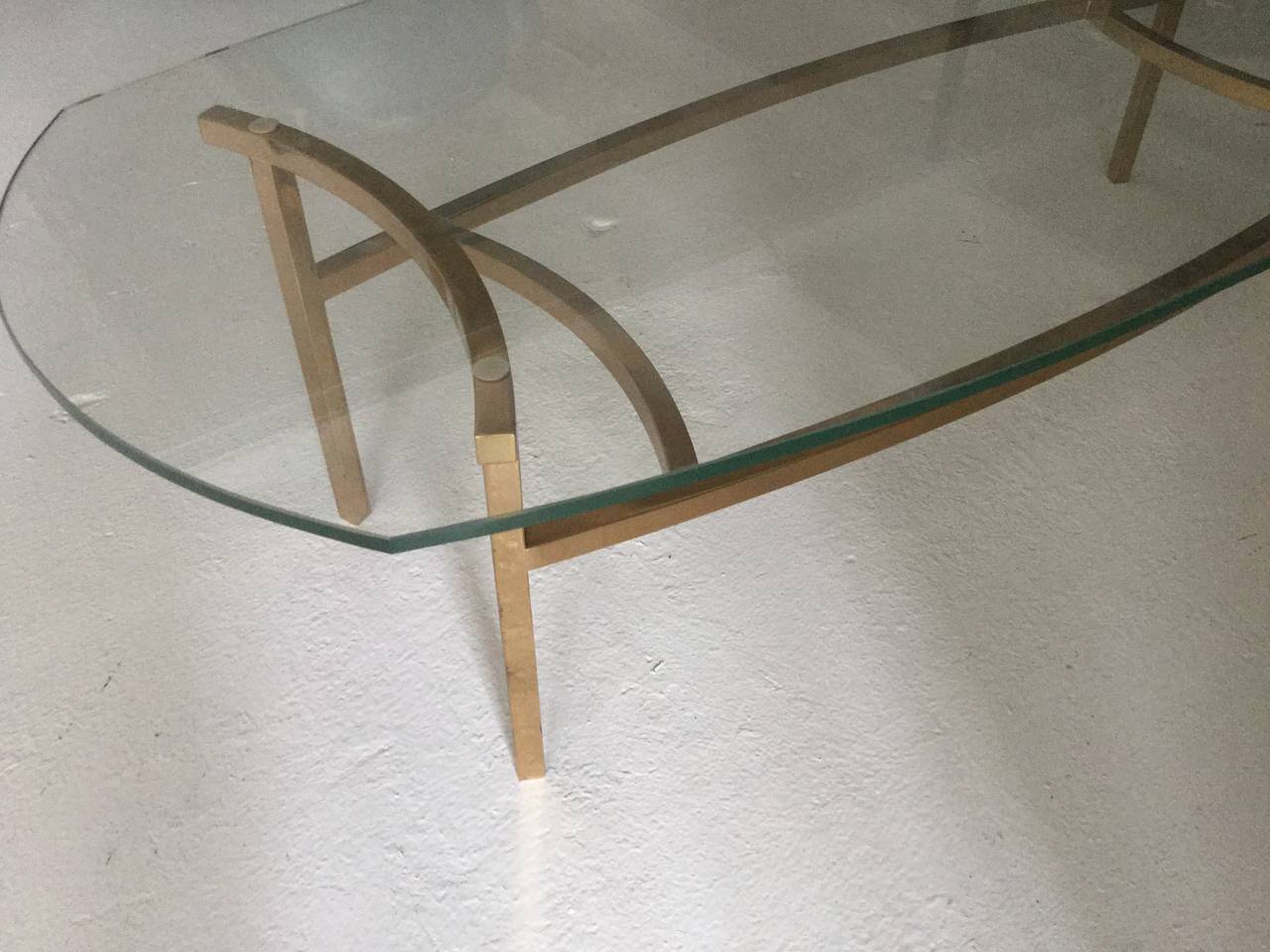 Elegant brass and glass coffee table.
with oval glass top supported by curved.
brass frame.
  