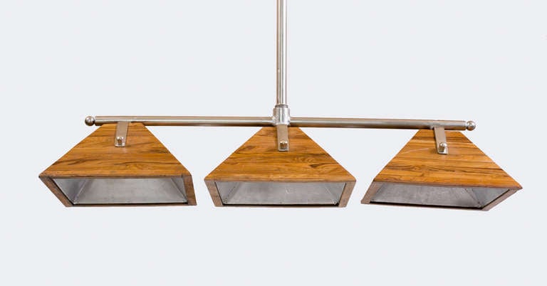 Three Light Pendant Light fixture featuring pyramid shaped 
Shades with laminated wood outer shell and metal reflector liner.
Mounted on nickel finished metal horizontal rod
Attached to the ceiling pol mount with chain.
Displayed @ ENTREPOT,
