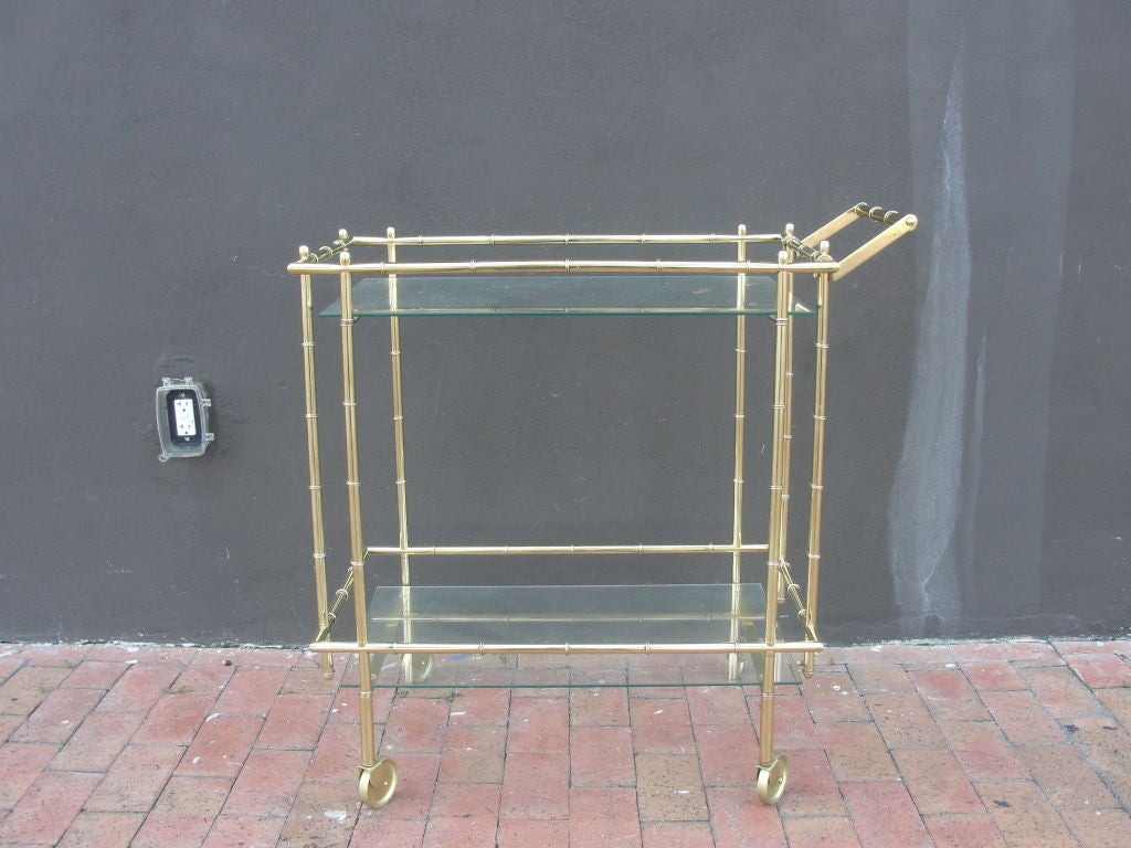 Simple, yet elegant - this faux bamboo brass barcart on wheels contains two glass shelves and is easy to roll.