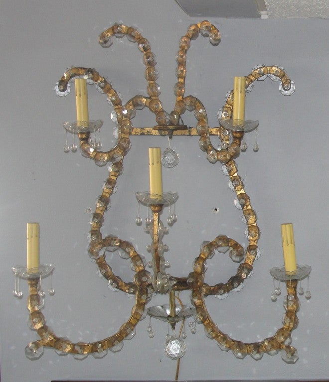 This pair of glamorous/large scale gilded iron wall sconces each have 5 arms and are overlayed with crystal glass details. Truly one of a kind!
Note: Some crystal have been replaced.