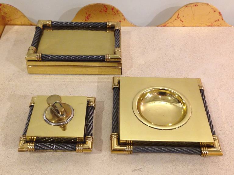 Steel mesh wire trimmed on brass ashtray, lighter and cigarette box.

Ashtray  — 6 1/2 in L x 6 1/2 W
 Lighter — 4 1/4 in L x 4 1/4 W
 Box — 7 1/4 in L x 5 in W