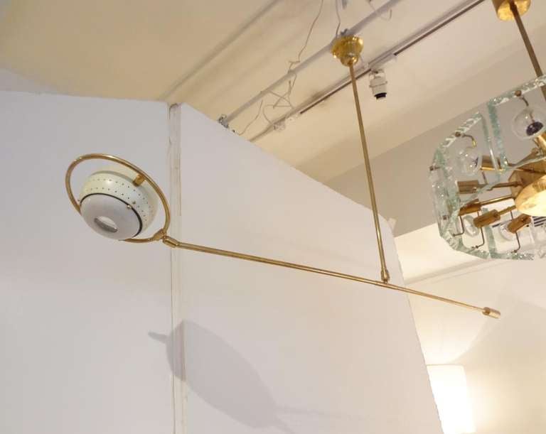 A very rare chandelier featuring a body in brass with a single hanging rod onto which is attached a counterbalanced brass rod. The counterbalanced brass rod features a round central brass frame in the middle of which is a perforated white lacquered