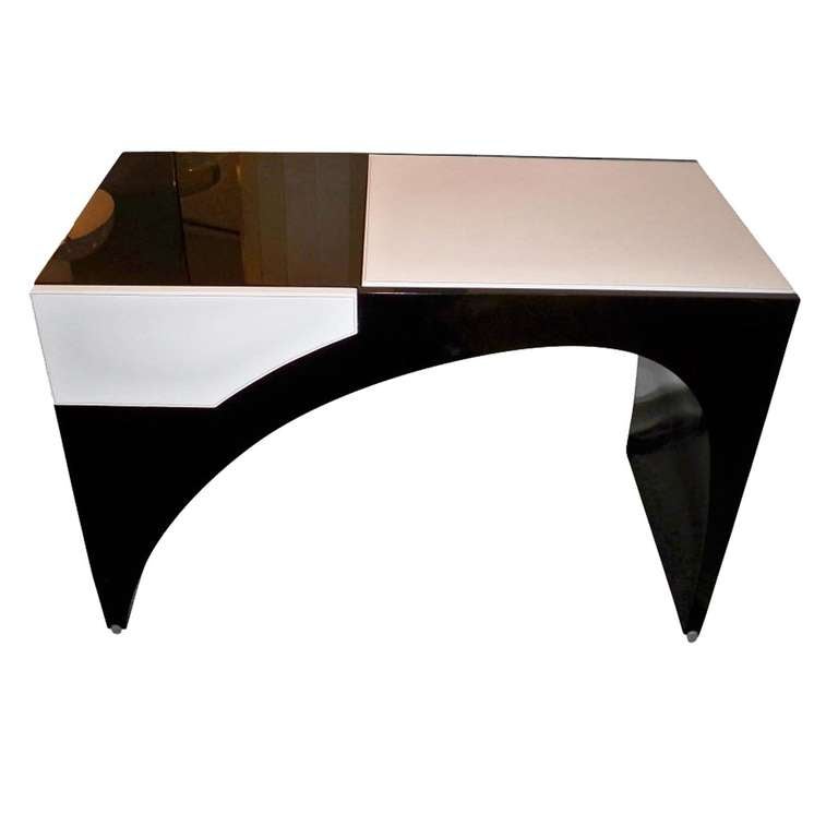A modernist dressing table featuring a body in black lacquer that sits on round bronze pole shaped feet with a asymmetrically shaped kneehole opening with a single drawer fronted in white leather and a top area, also covered in white leather which