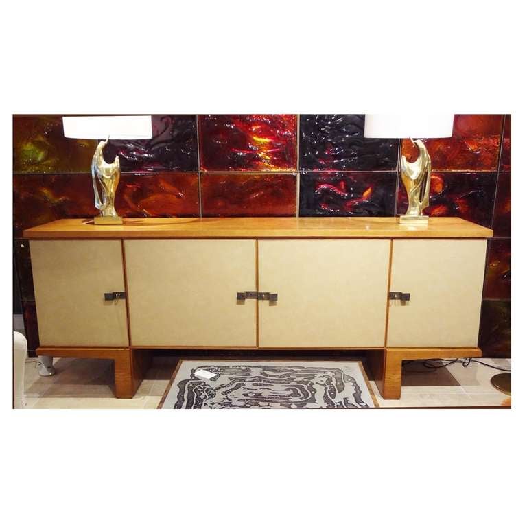 A rare and exceptional Mid-Century sideboard featuring a body in oak with four doors covered in original taupe colored textured vinyl. The sideboard also features solid bronze modernist pulls, a fitted interior with shelves and concave drawers and