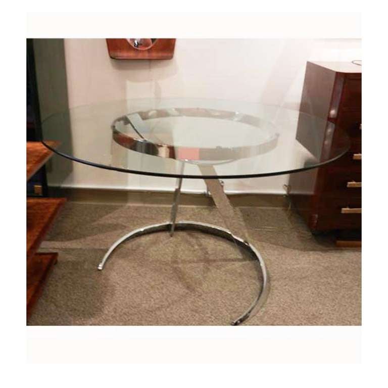 A round breakfast or center table featuring a modernist sculptural base in chromed steel which supports a round clear glass top.  France, circa 1970