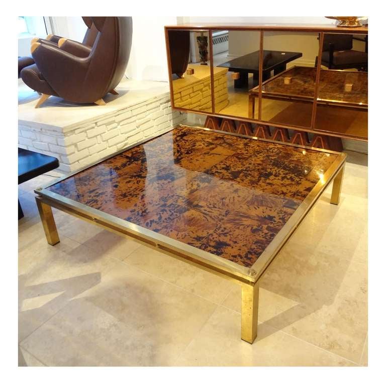 A rare and grand scaled square cocktail table featuring a frame in gilt brass with a floating top which has been inset in a mosaic of faux tortoise shell. The faux tortoise shell top has been divided into twenty five equal squares which are divided