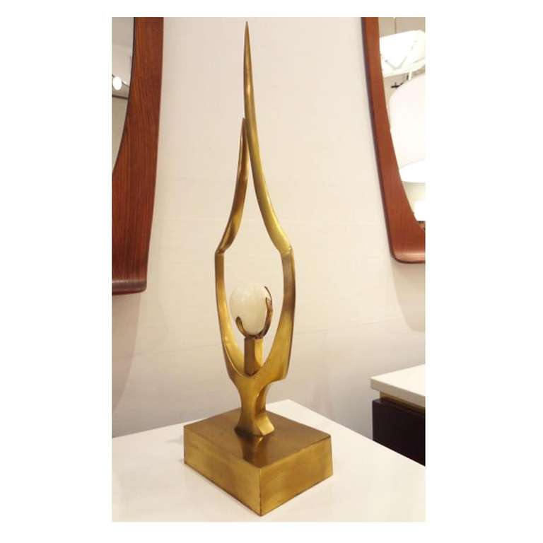 A sculpture featuring a body in brass with a central mounted egg shaped piece of white quartz. The sculpture is signed by the artist. Willy Daro, Belgium, circa 1968.