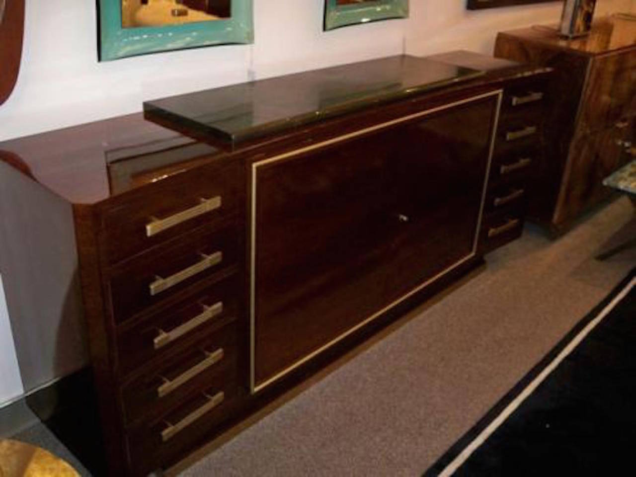 Important sideboard in Walnut featuring a concave bow shaped body which sits on a raised plinth base with a gilt bronze foot. The sideboard also features two central doors with interior shelving banded in gilt bronze which are flanked on either side