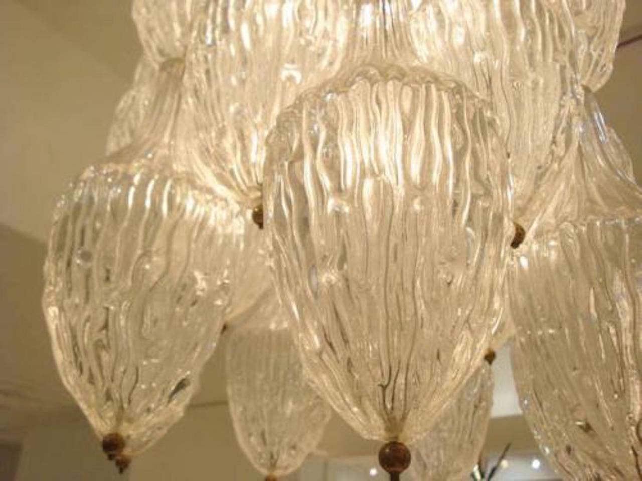 A chandelier featuring a body that consists of rows of handblown textured glass bottles that hang from a metal frame and act as a light diffuser for the inner lamps by Antonio Salviati, Italy, circa 1968.