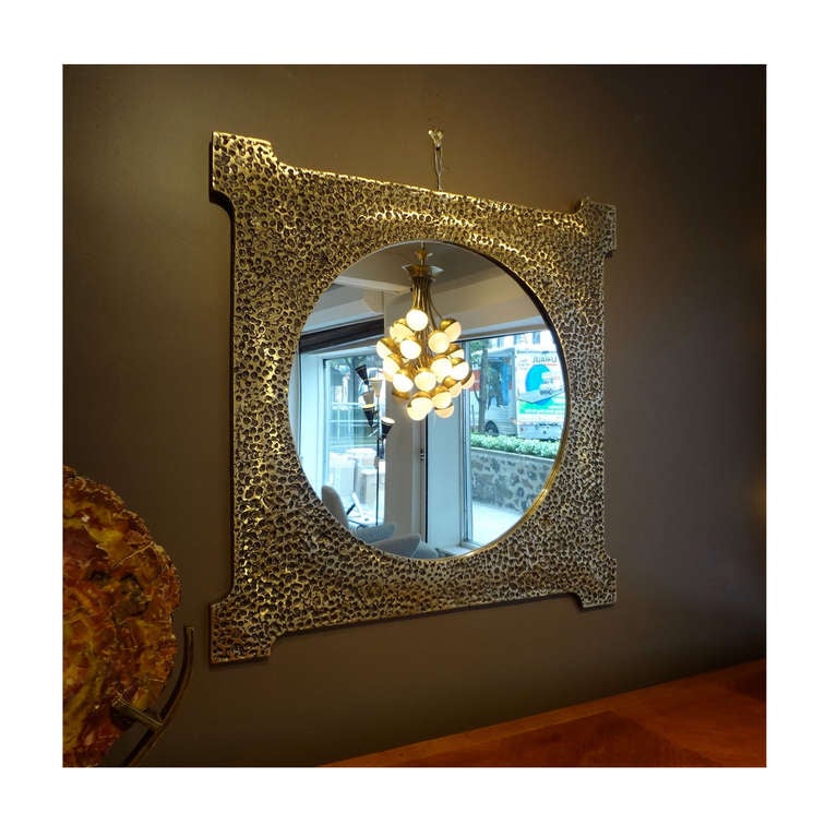 A large scaled important wall mirror featuring a frame in sand cast bronze with a round central clear mirror. The mirror is fully documented and comes from the artist's families private collection where it has been since its creation. Luciano