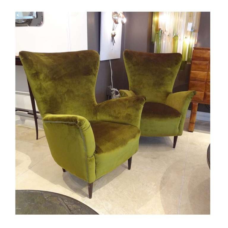 A pair of mid century modernist club chairs featuring shaped backs and integrated splayed armrests. The clubs also feature tight seats and tapering Mahogany legs. The clubs have been re-upholstered in a green velvet. Carlo di Carli, Italy circa 1950.