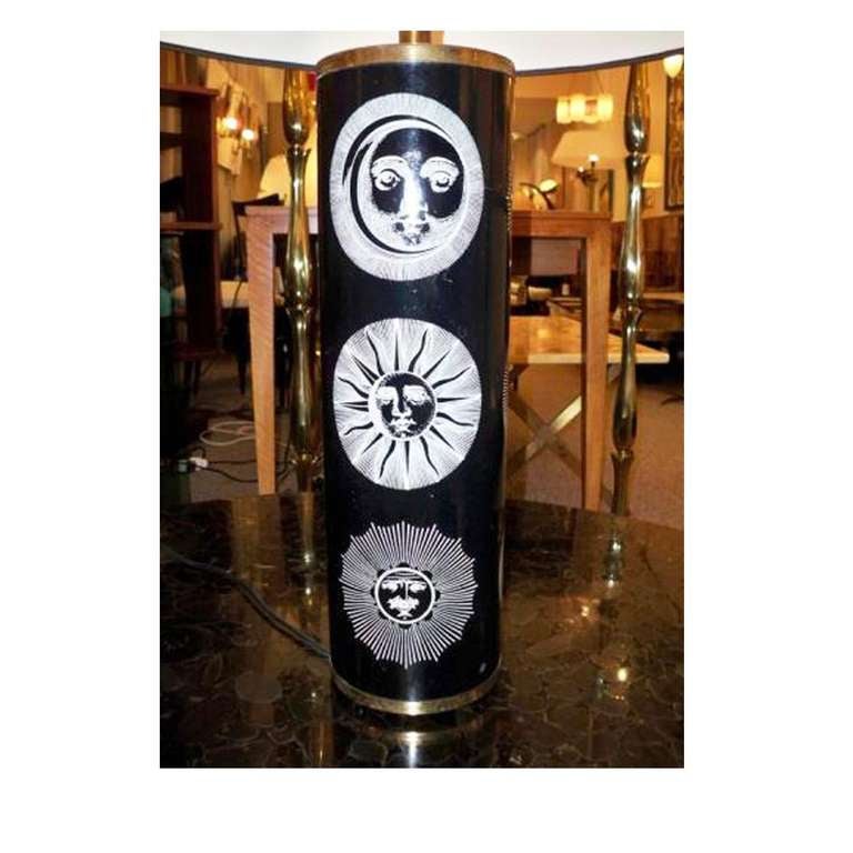 A large scaled table lamp featuring a cylinder shaped body with a brass base, cap and fittings decorated with one of Fornasetti's most iconic patterns, the sun and moon in black and white. Piero Fornasetti, Italy, circa 1955.