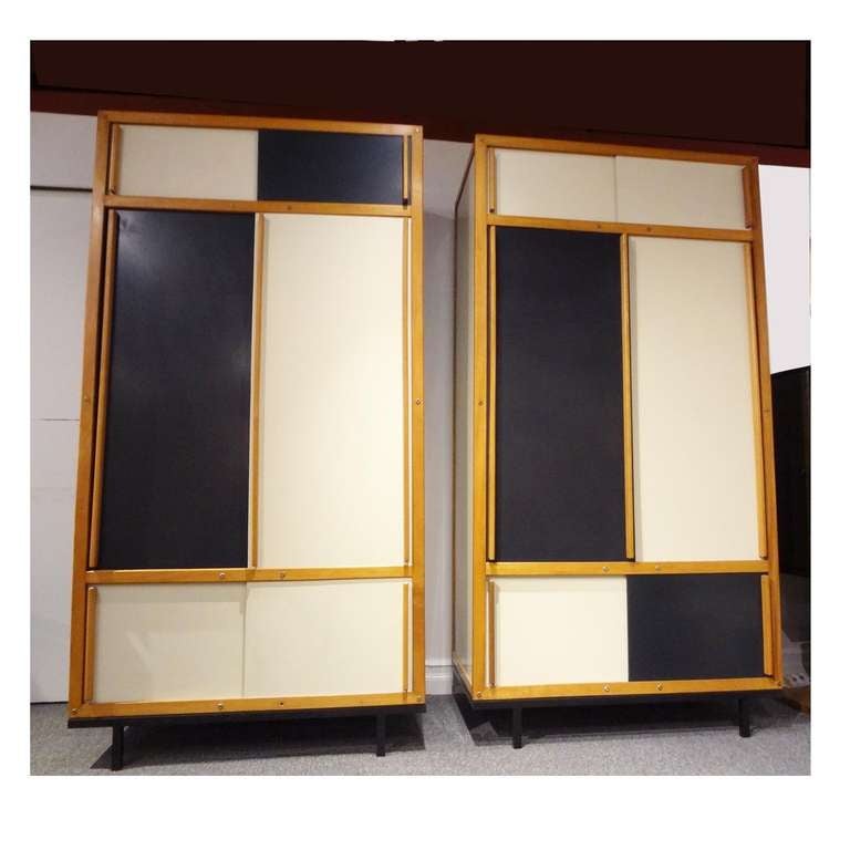 A rare pair of cabinets featuring Masonite panels in black and cream. Each of the cabinets features top, center and bottom compartments all with sliding doors. The cabinets also feature color blocked patterns that are opposite of each other and