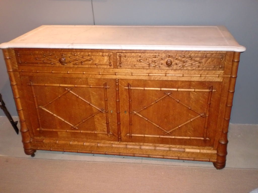 French Faux Bamboo Sideboard with 2 top drawers atop 2 cupboards doors with center shelf on one side.Original marble with rounded front ends.Originally had side and backsplash