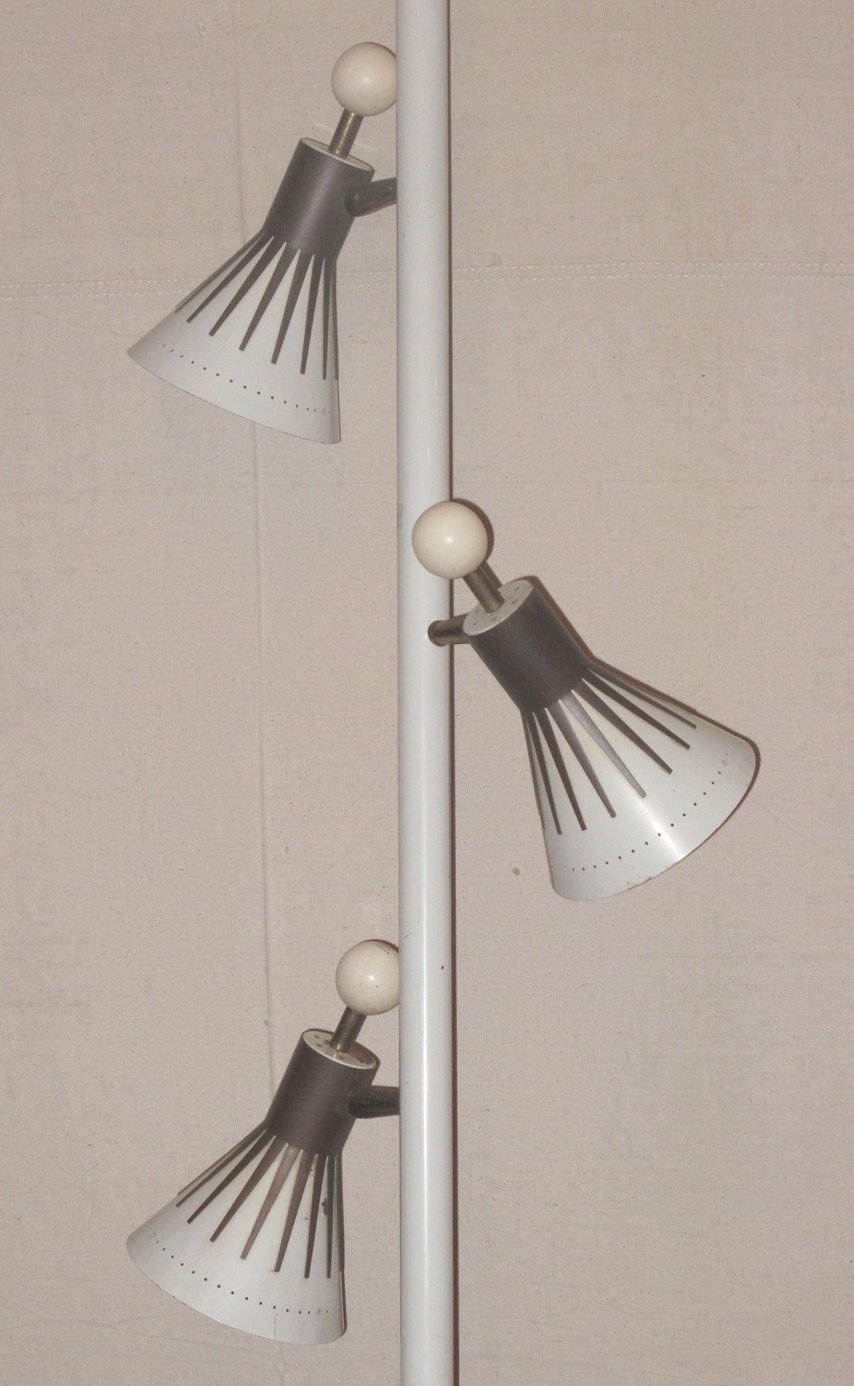 The brass and painted metal pole mounted with three lights with painted shades mounted with metal ray decoration and wood ball finials. Pole is 105