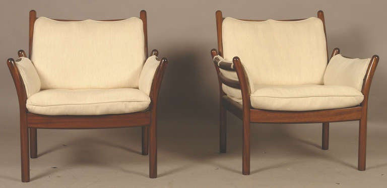 The mahogany chairs with out-curved post arms and with upholstered seat cushions, backs and sides.  Circa Early 1960s by Danish Designer lllum Wikkelso.