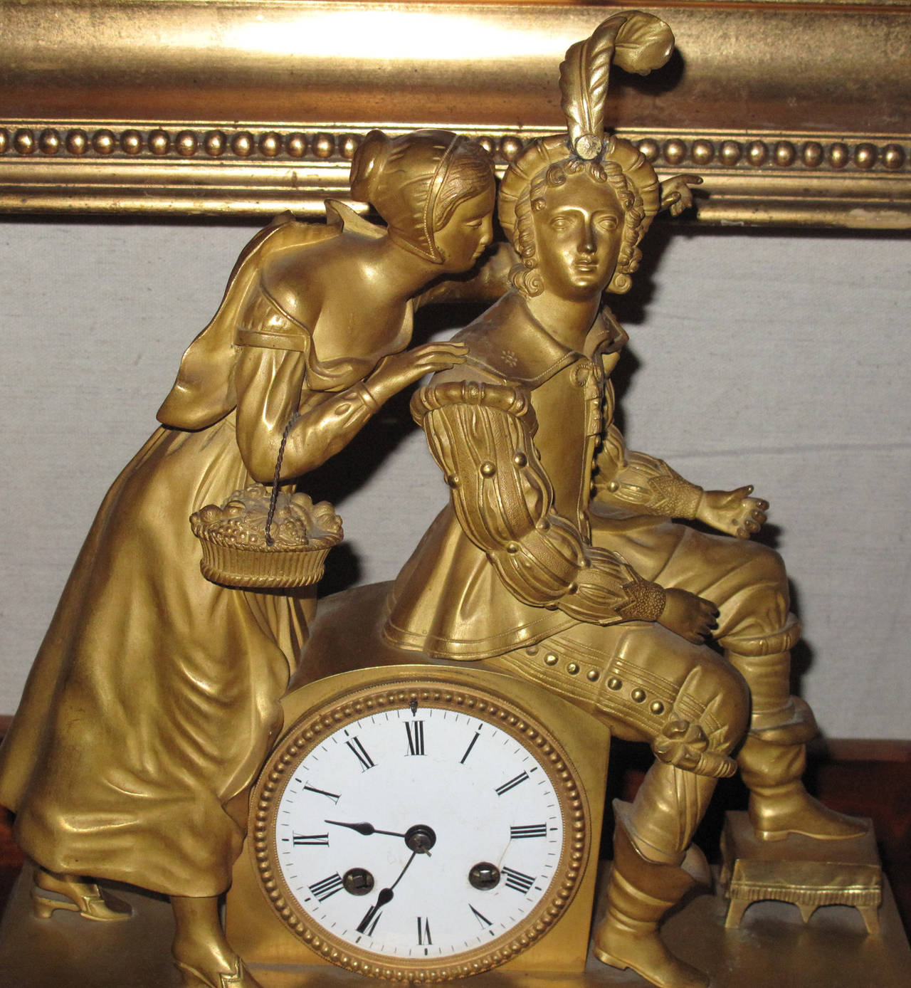 French Empire ormolu mantel clock with a female and male figure in fancy dress sculpted in the round.  The base cast with neo-classical ornamentation. 
Circa 1815-20