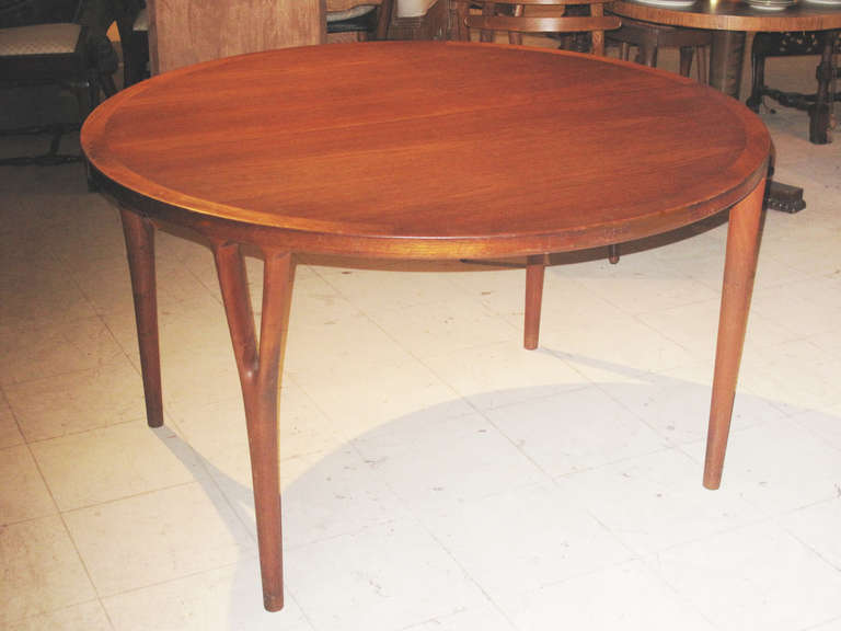 The cross-banded top on four open V form legs.  The table with two leaves each measuring 23 3/4