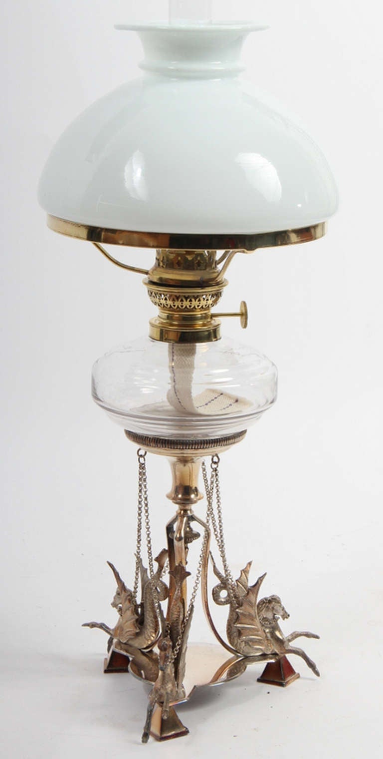 English Oil Lamp with Brass Mounts and Opaline Shade.  The silvered base with three hippocampi supports.  190s0s-1930s. The base marked with silver stamps.