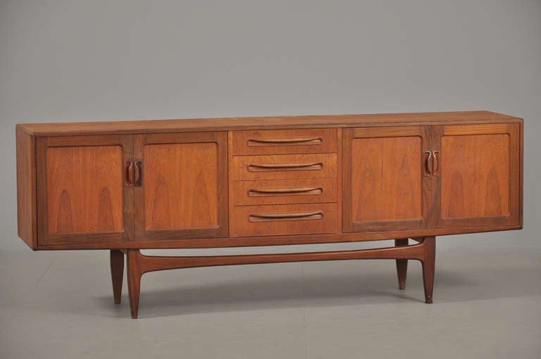 The teak sideboard with four pull out center drawers flanked on each side with two doors opening to an interior space.  Was formerly fitted with shelves, shelves are missing but shelves could easily be made for this piece.  Manufactured by a Danish