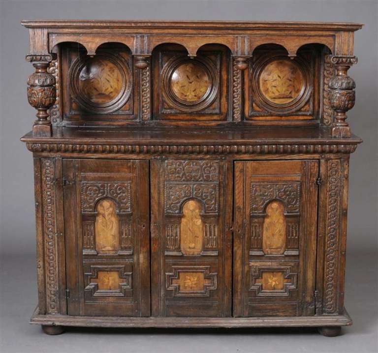 Wonderful dining room buffet in the Jacobean style from England, in oak with inlays.  The case with two doors and central panel, on bun feet.  The case with early floral marquetry insets. Mid 19th century and comprised of earlier elements.