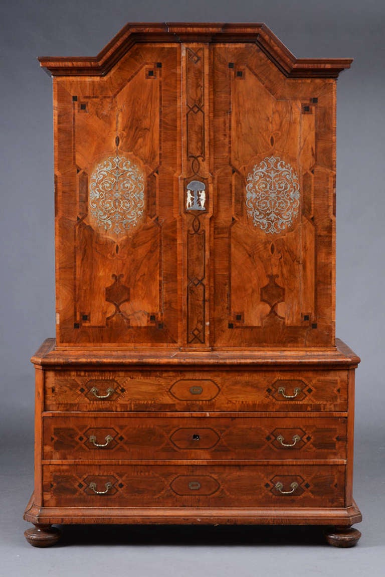 Early 18th Century South German Baroque Cabinet on Chest.  The arched cornice over two parquetry inlaid doors with vine work pewter medallions on each side.  The door with a central lock-plate of pewter and bone depicting Adam and Eve flanking the
