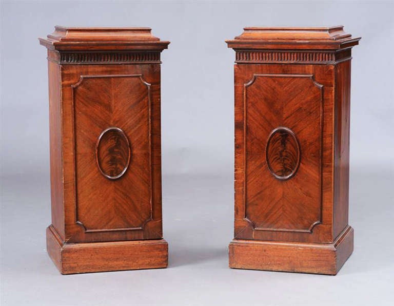 A Pair of George III Mahogany Pedestals of Nicely Figured Mahogany.  The molded tops over fluted friezes, each pedestal with center lozenge shaped moulding within a outer molding with in-curved corners, the pedestals on plinth bases.  One pedestal