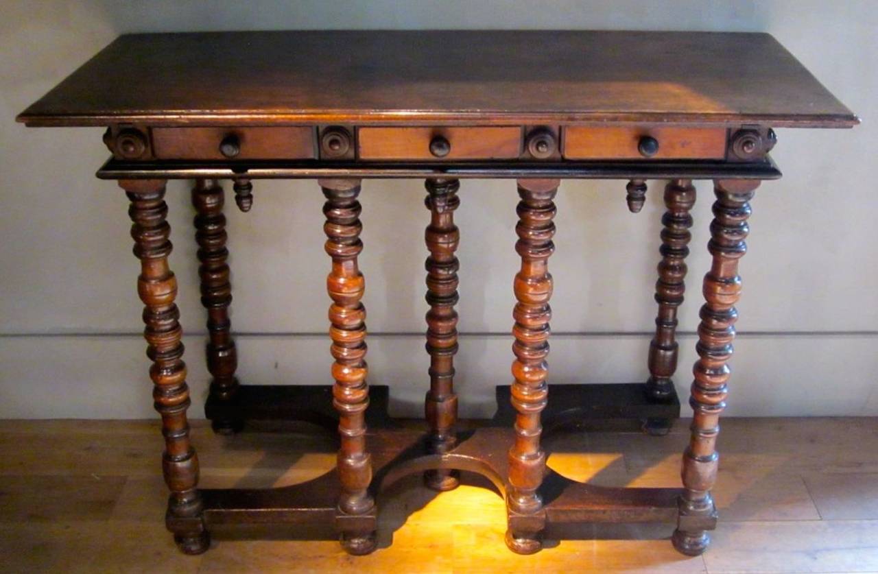 Italian 17th century walnut spool leg console table with three drawers. 
The interesting cut out base connects the table legs.
Arrives in April.
