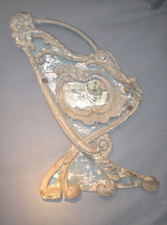 This unusual mirror with a very ornate carved frame, was originally the side to a merry go round carousel. It makes a great decorative wall mount or can be used as a mirror. The mirror is located in the center of the frame. Great washed blue patina.