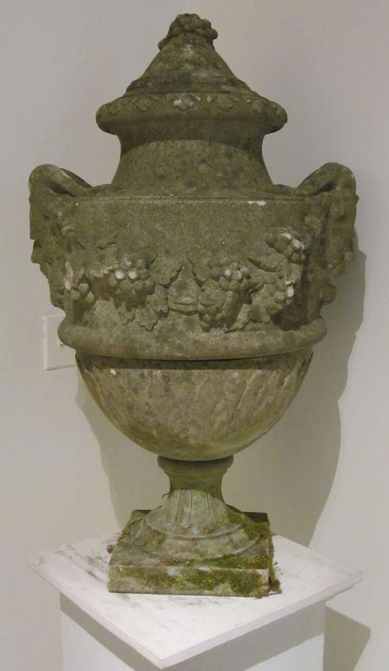 1940's English rams head stone urn with lid.
Handles at the sides flow into a a ram's head and a wreath of grapes adorns the body of the urn as well as the top of the lid.