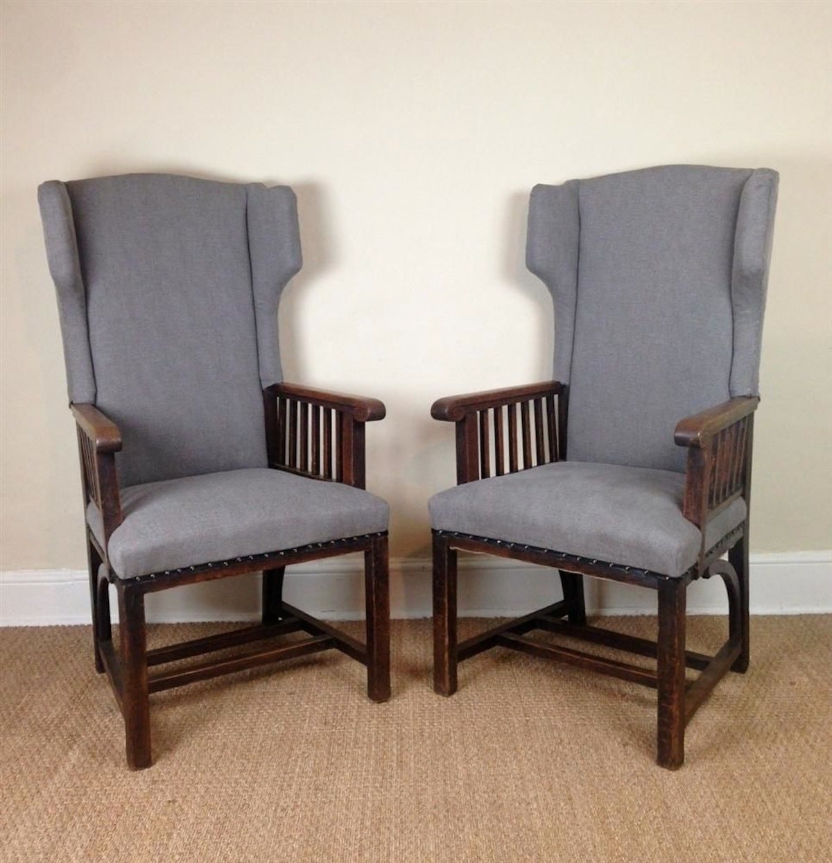 English pair of 1900's Arts and Crafts high back upholstered wing chairs.  The wooden arms and legs are exposed.
The chairs have been recently reupholstered in blue and grey cotton fabric.
They are in excellent condition and will arrive in April.