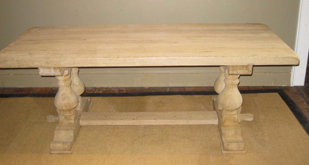 This bleached farm table has a classic thick top and double finial legs. The table has been sanded and bleached from its original dark patina.