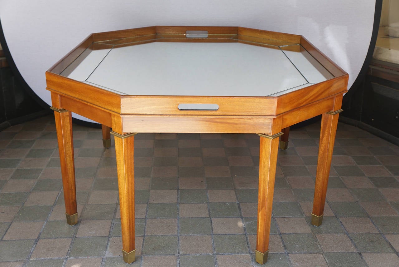 This large coffee or cocktail table is designed by Ralph Lauren and carries his brass label. The table is constructed of fine grained light mahogany making it modern and sophisticated. The top is mirrored in many sections corresponding to the shape
