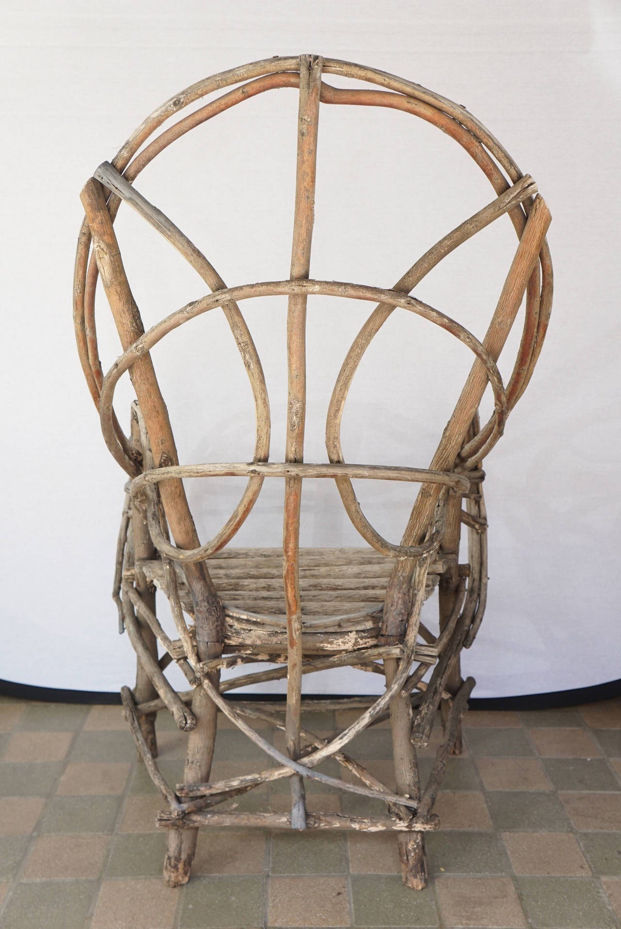 This fine old chair made to grace an Adirondack lodge's deep porch or lawn was made circa 1910.  Made most likely on site at a lodge and found in Upstate New York it is constructed of willow limbs & twigs cut and nailed together. The nails are