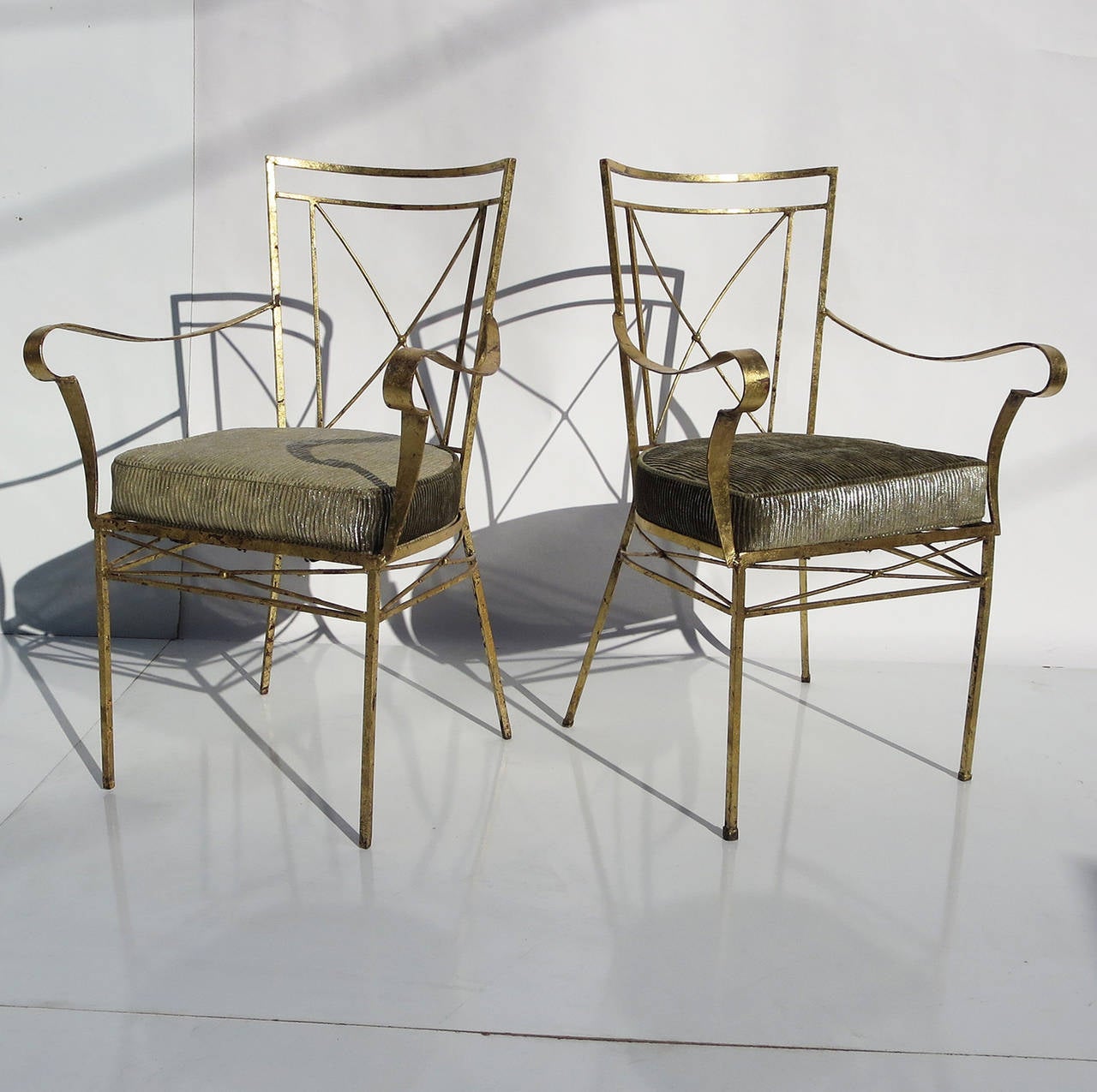 This lovely pair could be equally blended into a modern or traditional setting, and look perfect in either venue. The frames are formed iron, and finished in a distressed gold leafing. The cushions were recently replaced with a wonderful metallic