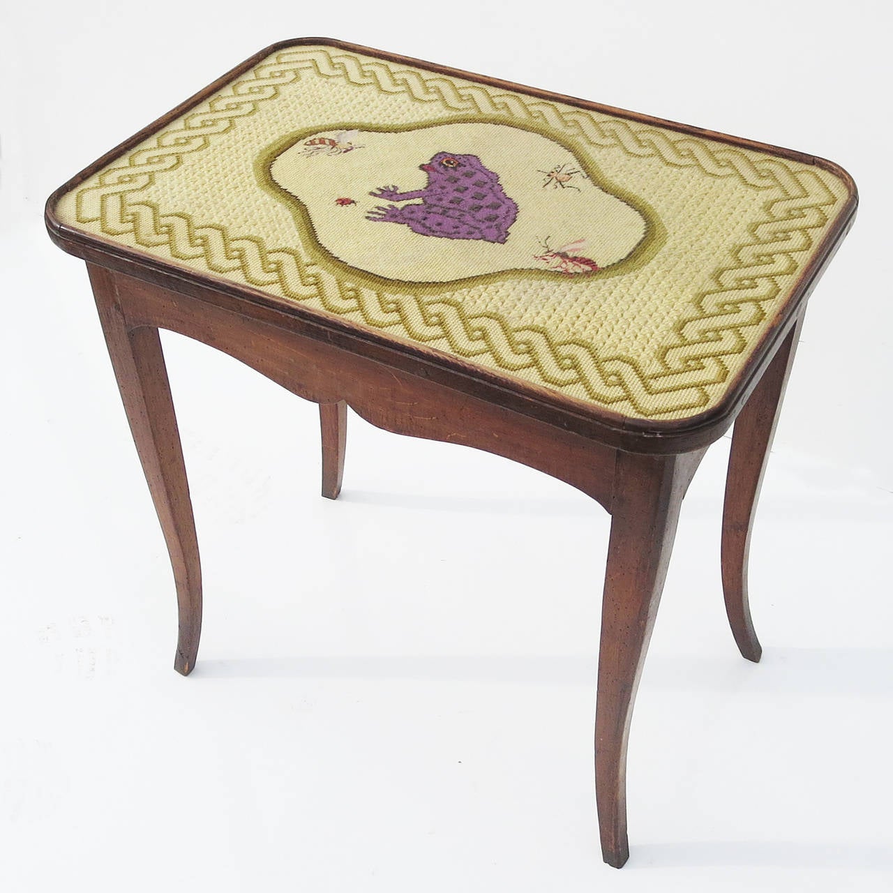 This super charming table features a needlepoint embroidered top surface of a frog and insects, executed in the highest quality. There is a clear glass top surface to protect the work. The frame is a dark stained fruitwood, with a single drawer. The