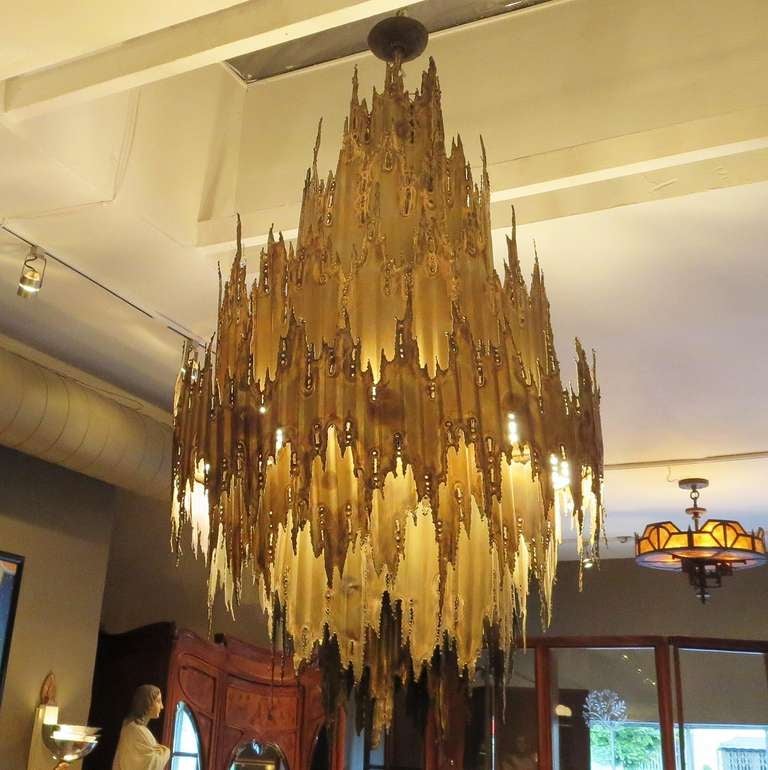 The largest of Greene's series for the Feldman Company, the chandelier measures sixty six inches tall, and thirty seven inches in diameter. The perimeter houses eight standard bulbs, and one in the bottom downward center column. The lamp is classic