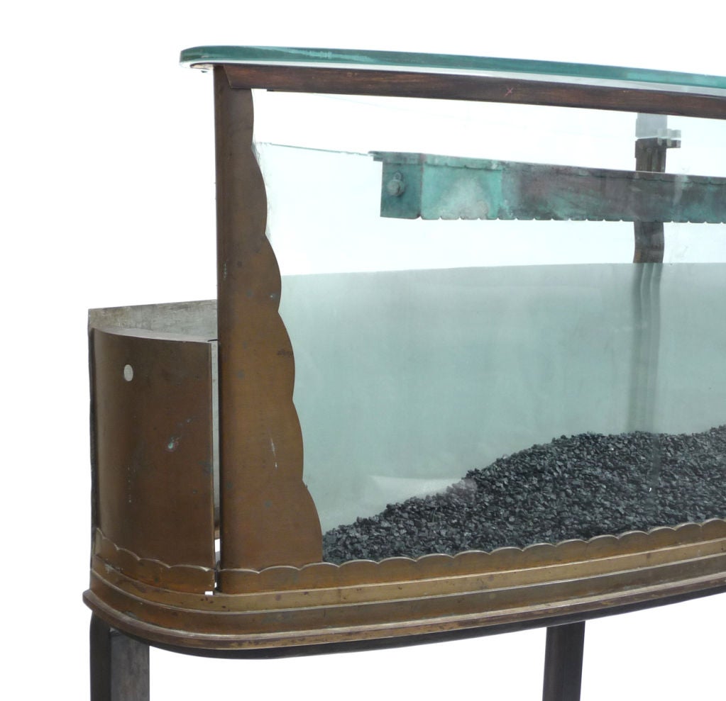 A very beautiful and sleek design, combined with a warm patina, add up to one of the most fantastic aquariums we have encountered. The thick curved glass front and rear panels join behind the bronzed end panels, cut in a cascading stepped pattern.