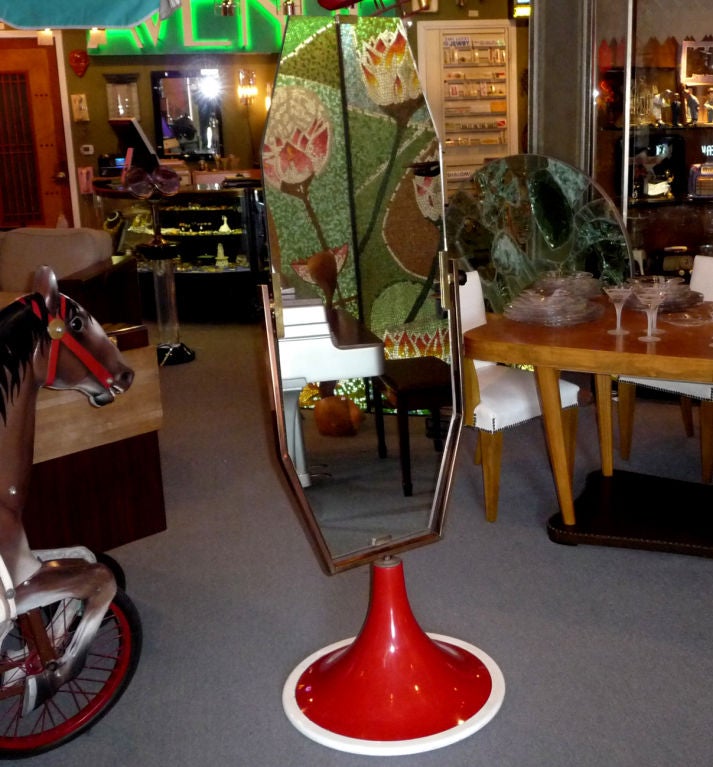 A decidedly modern twist to the traditional dressing mirror. This Pop design begins with a white lacquered wooden base, in which a red enameled metal cylinder is housed. Capped by a solid brass rosette, a brass and copper frame house the octagonal