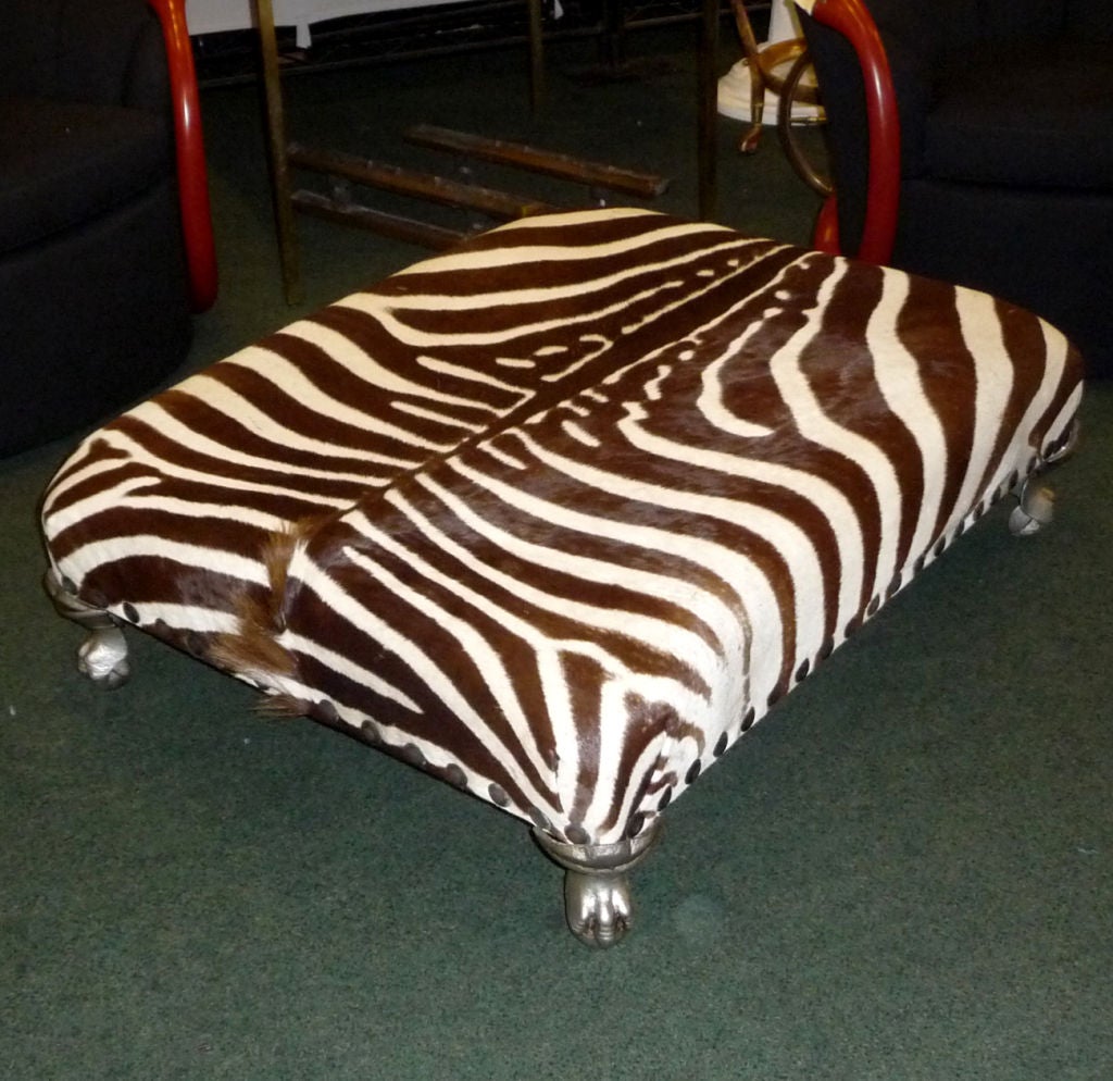 An extremely glamorous and exotic treatment to a low lounging bench. The original hide is in very fine condition, and displays beautifully. A tasteful border of bronzed studs create a pleasing contrast to the stripes of the skin. The legs are a cast