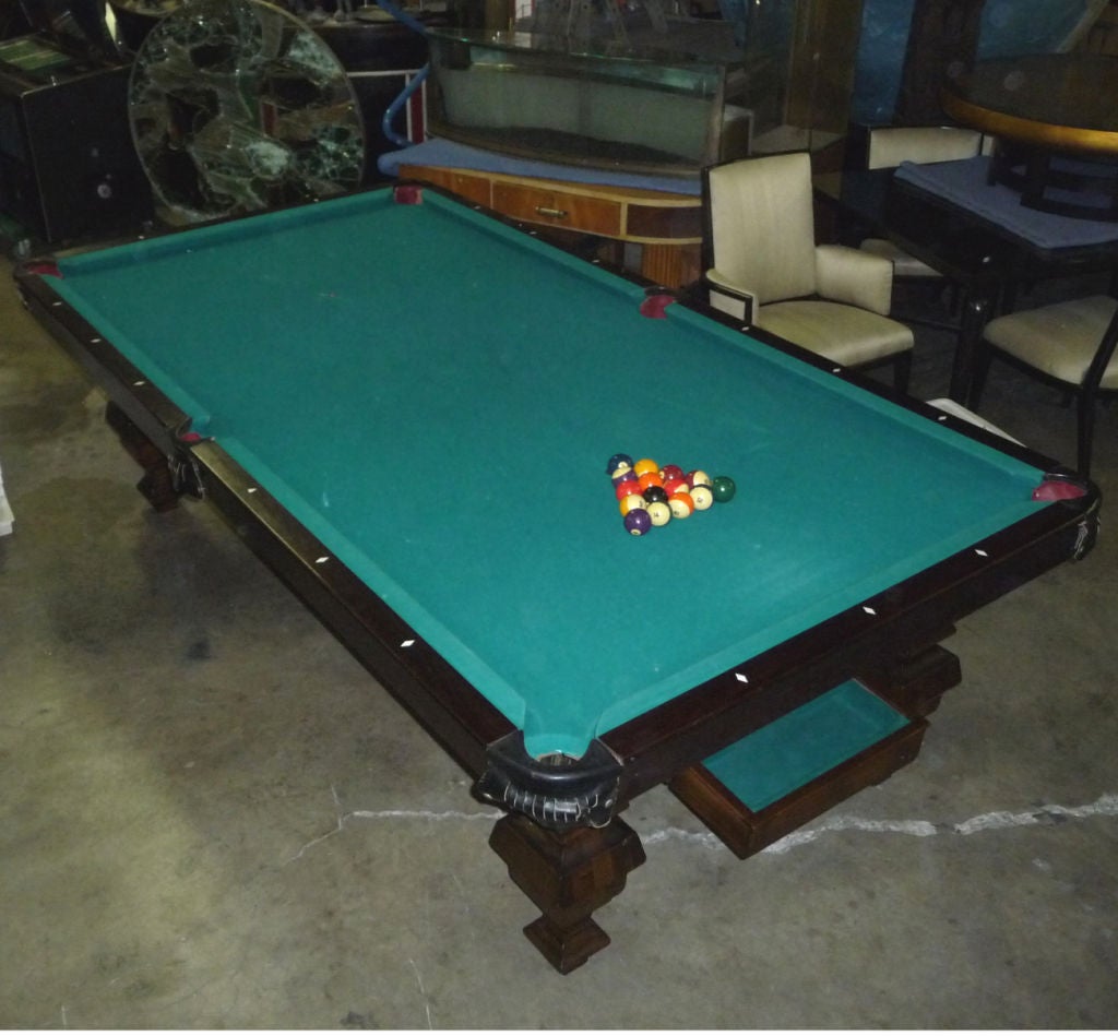 A beautiful table in dark mahogany and rosewood. This full scaled (9 foot) table also features a ball return system, returning all played balls to the tray at the head of the table. Rails are rosewood, surrounded by leather skirted pockets. The