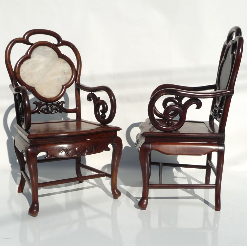A gorgeous pair of hand carved chairs that display both strength and delicacy. They have recently been polished, and display beautifully. The backs are set with matte marble in a clover form. They are extremely elegant, without being over decorated