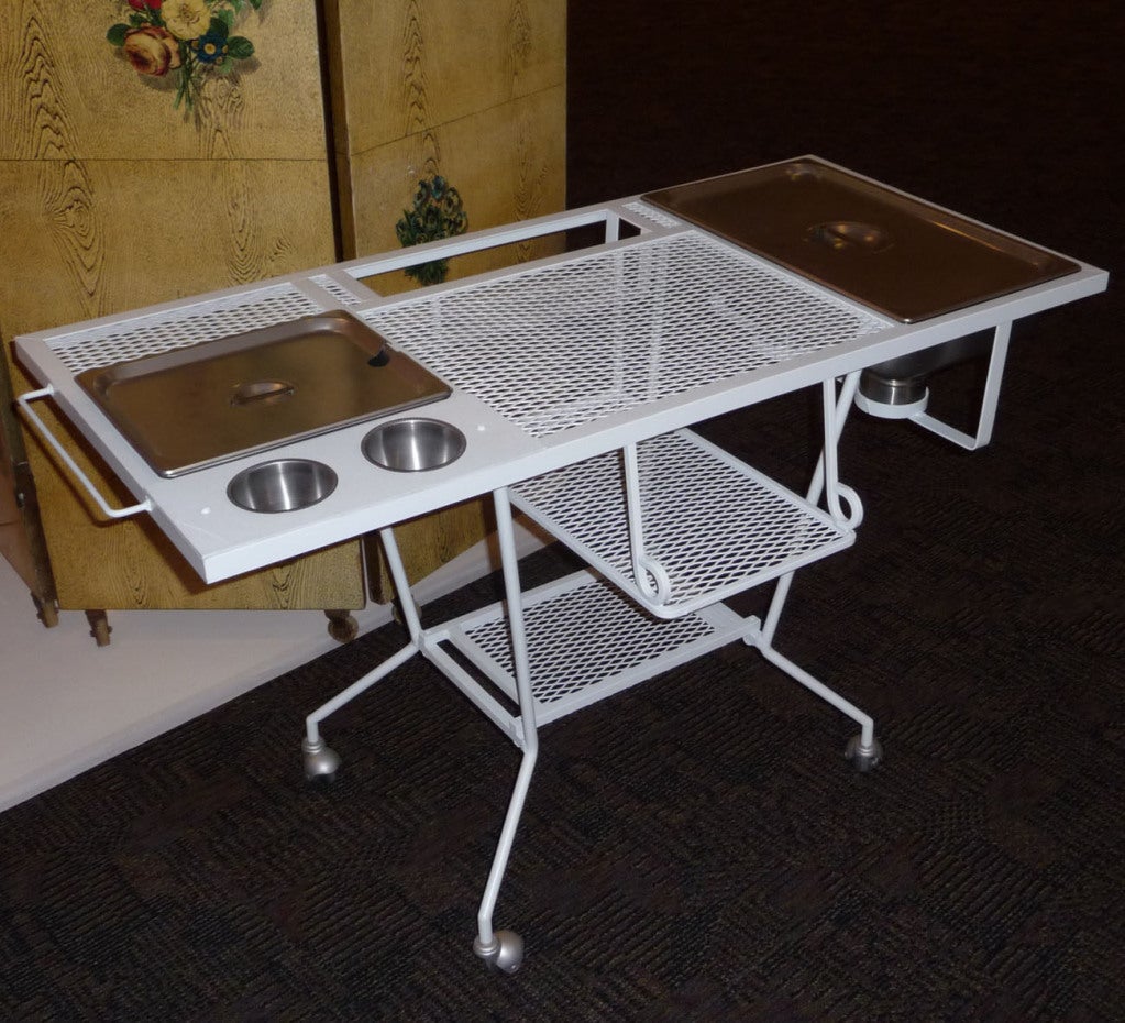A pleasing and practical design, This painted steel cart combines great form with function. The right side features a steel serving tray, with two heater pots below. The left side features another non heated serving tray, with two condiment bowls.