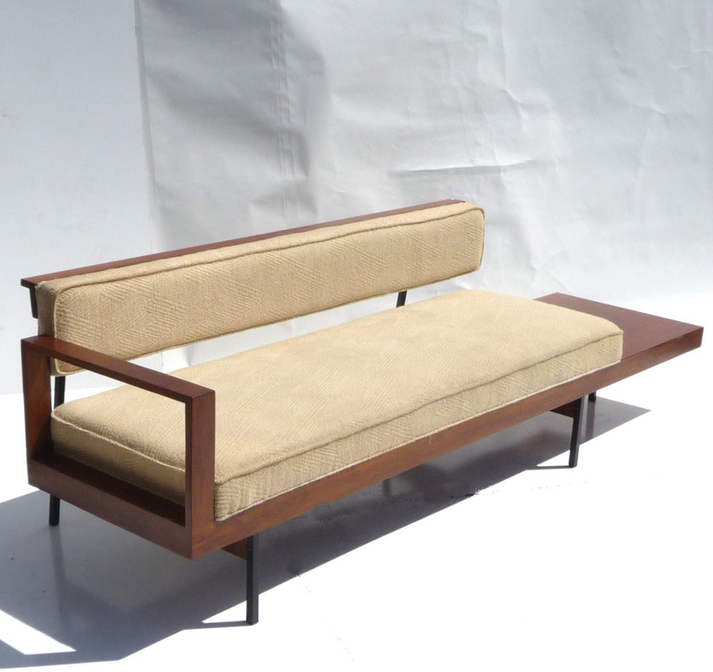 A tasteful and architectural form, this lovely pair have a strong Paul Laszlo influence. They were designed and executed by Hy Farber, an artist represented in the permanent MOMA collection. The walnut is refinished, and the upholstery has been